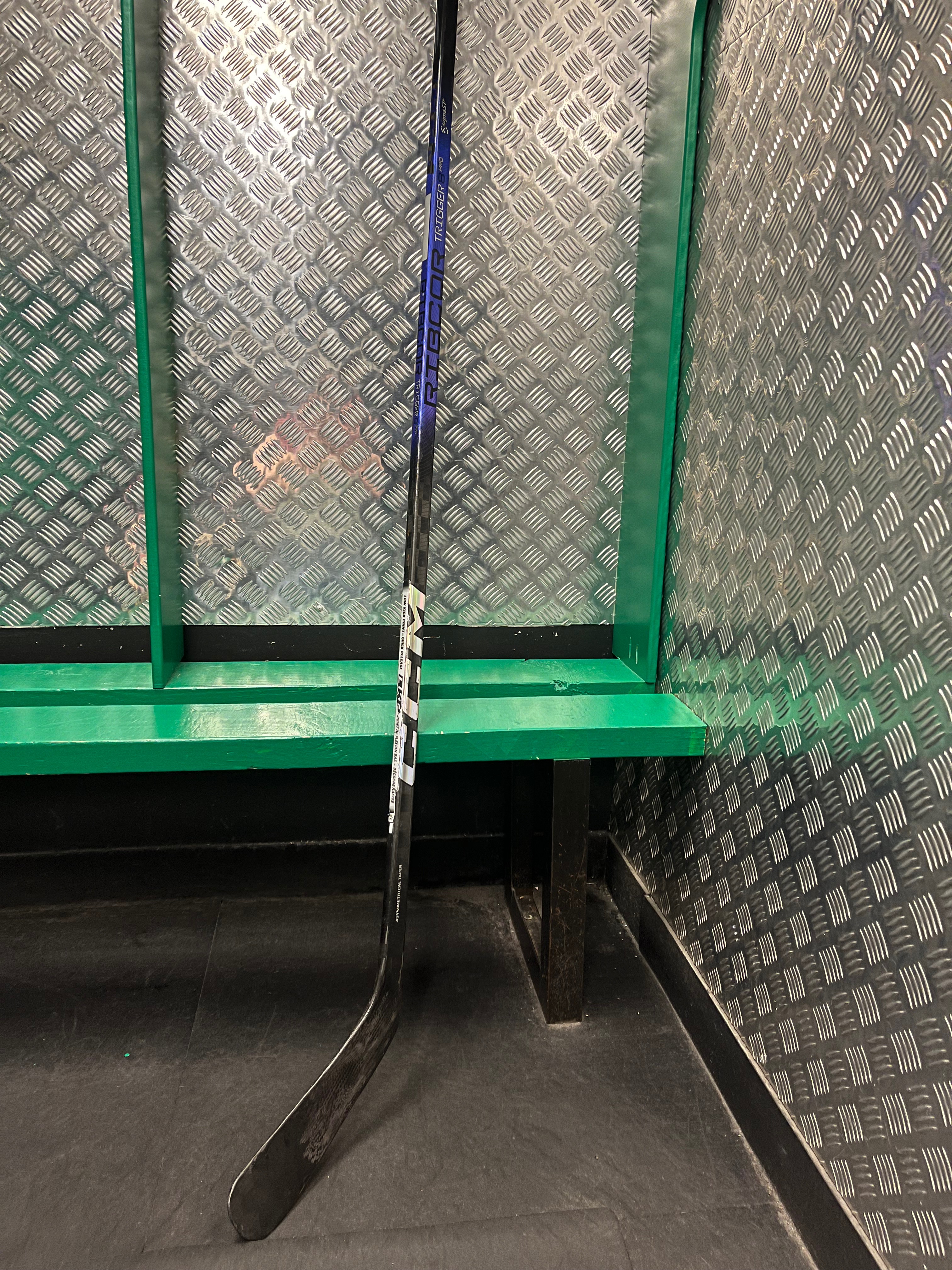 Repaired CCM Ribcor Trigger 8 Pro stick leaning against a locker room bench